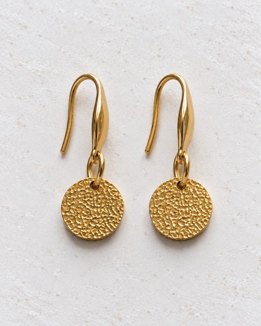 Pendientes Halo de Hanalima: disco dorado martillado con gancho de acero inoxidable, packshot frontal