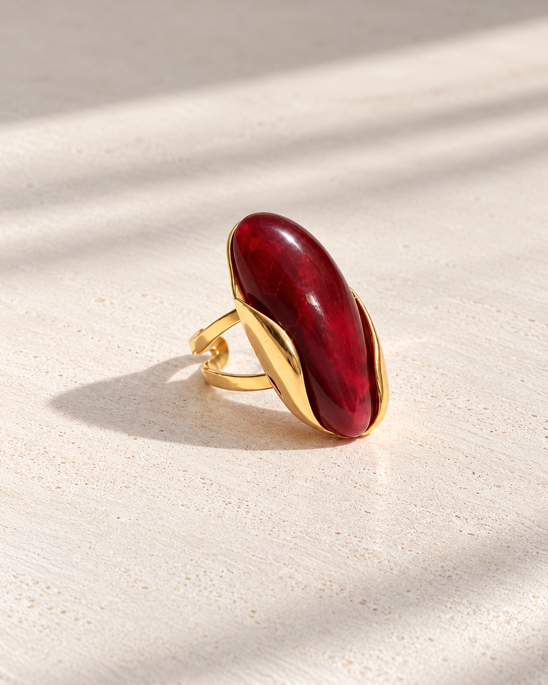 Anillo Carmela con piedra roja sobre cemento blanco