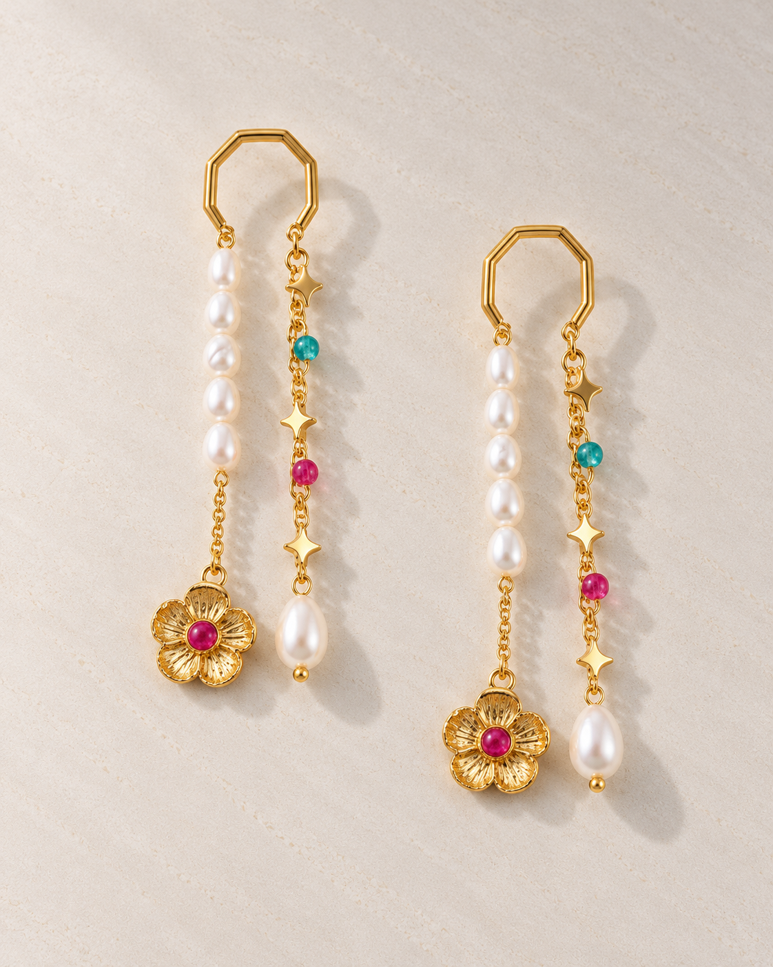 Pendientes Odile con perlas y flor dorada sobre cemento blanco